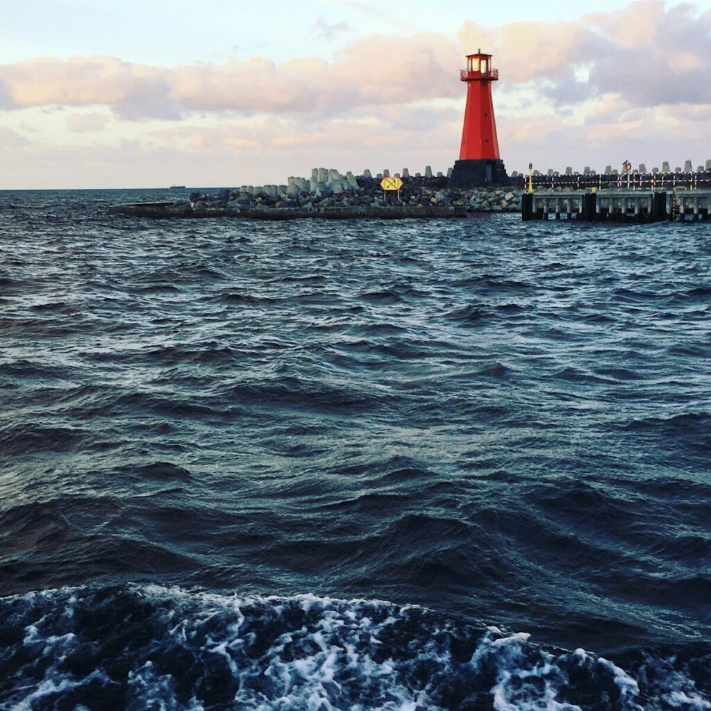 red and white lighthouse near body of water during daytime